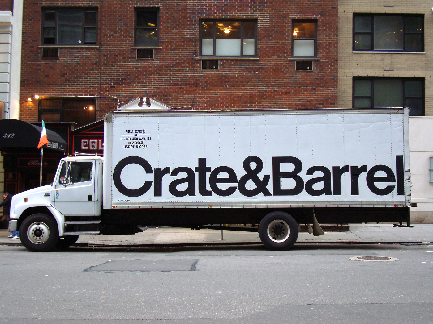 photo of a white truck parked on a city street with the black Helvetica Crate and Barrel logo on the side