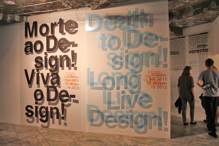 installation piece with large black and blue helvetica printed on acrylic or glass over a white wall