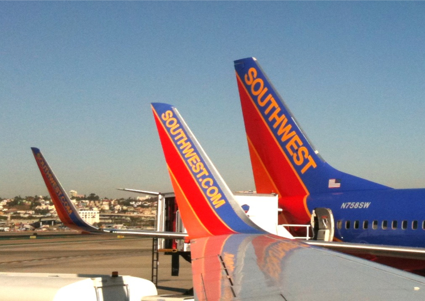 photo of the former blue, red, and orange helvetica southwest airlines logo on the tail of three planes sitting on a runway